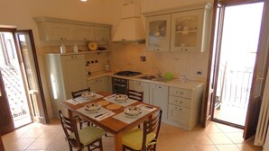 A kitchen with a dining table set for four, equipped with chairs, a stove, and a sink. - SCAPPO IN UMBRIA, la casa di Eude (Assisi)