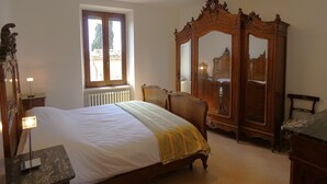 A bedroom with a bed, wooden wardrobe, and a window with a view. - SCAPPO IN UMBRIA, la casa di Eude (Assisi)