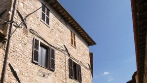 A stone building with a wooden door, arched windows, and a metal gate. - SCAPPO IN UMBRIA, la casa di Eude (Assisi)
