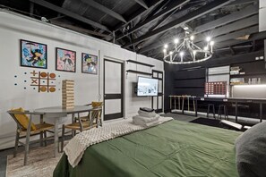 A room with a bed, a table with chairs, a television, and artwork on the walls. - Marvin`s Gardens: Fenced Yard, Game Room, Pets! (Irondale)