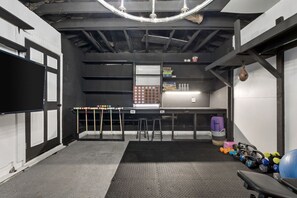 A gym with exercise equipment, a table with balls, and a wall-mounted punching bag. - Marvin`s Gardens: Fenced Yard, Game Room, Pets! (Irondale)