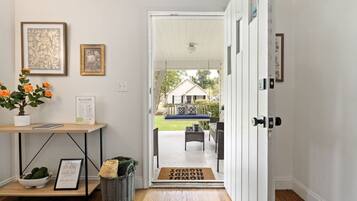 A clean, well-lit entryway with a wooden floor, a welcome sign, a framed picture, and a potted plant.