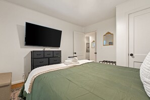 Un dormitorio con una cama, un aparador, un televisor y una puerta.