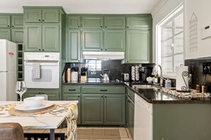 A kitchen with green cabinets, a white refrigerator, a coffee maker, and a sink. - Marvin`s Gardens: Fenced Yard, Game Room, Pets! (Irondale)