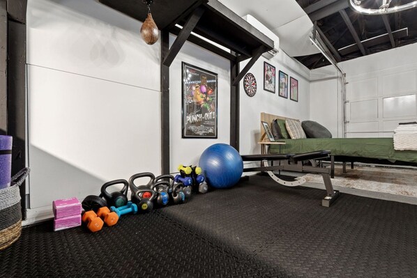 Un gimnasio con equipo de ejercicio, un saco de boxeo y una cama con cubrecolcha verde.