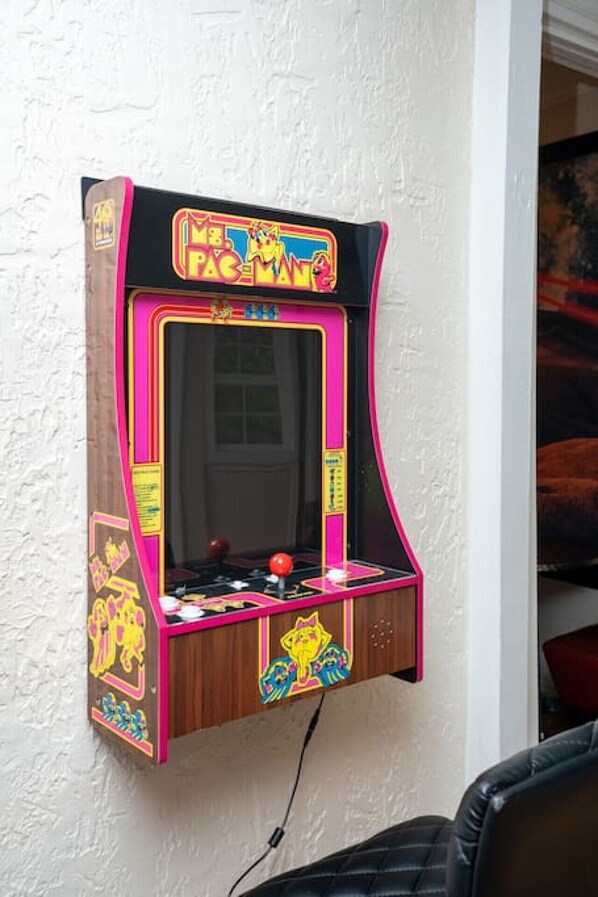 A Pac-Man arcade machine mounted on a textured wall.