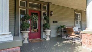 A porch with a red door, potted plants, and outdoor furniture. - The Glen Iris Getaway (Birmingham)
