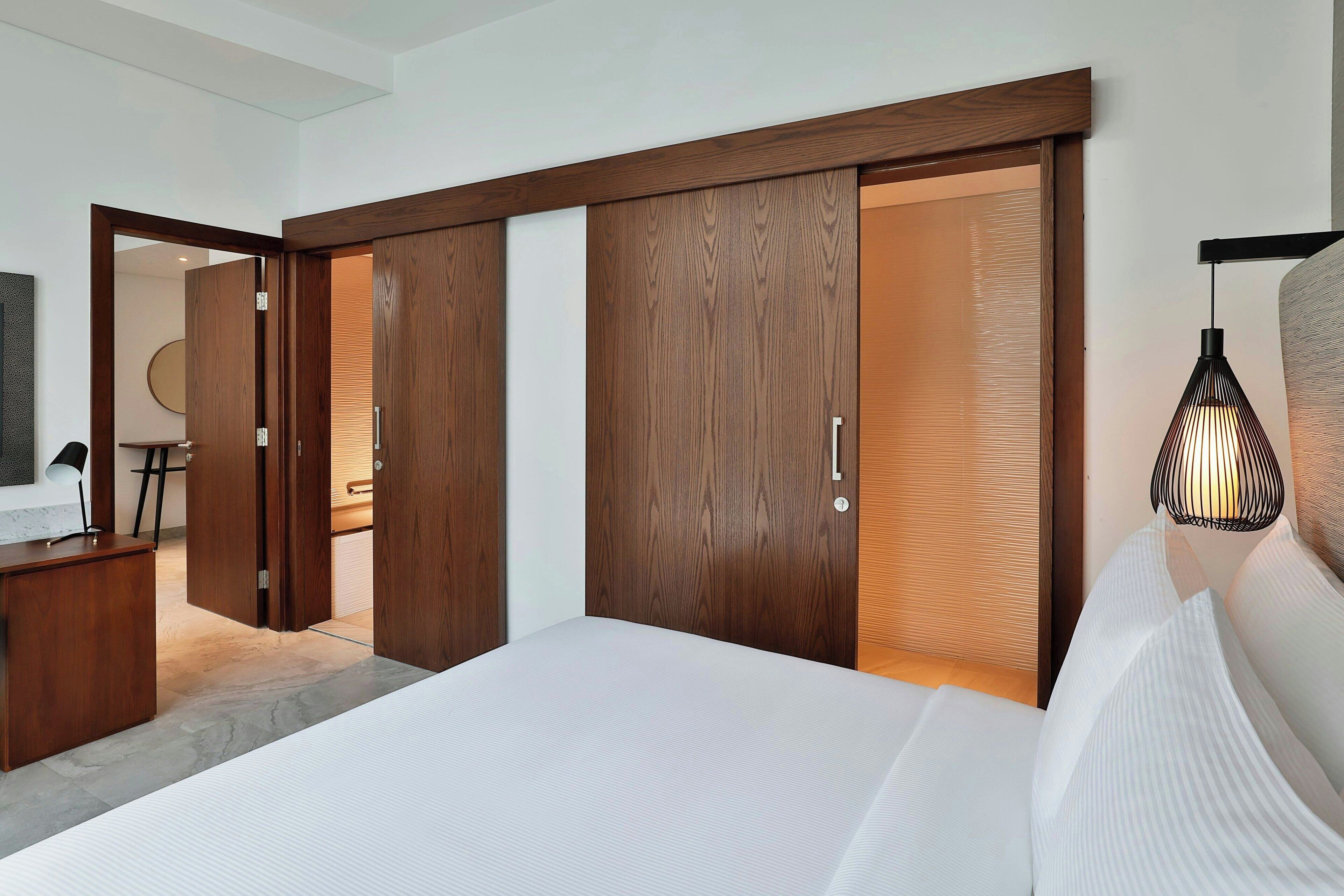 Ein modernes Schlafzimmer mit einem großen Bett, einem Holzschrank und einem Schreibtisch mit Lampe.