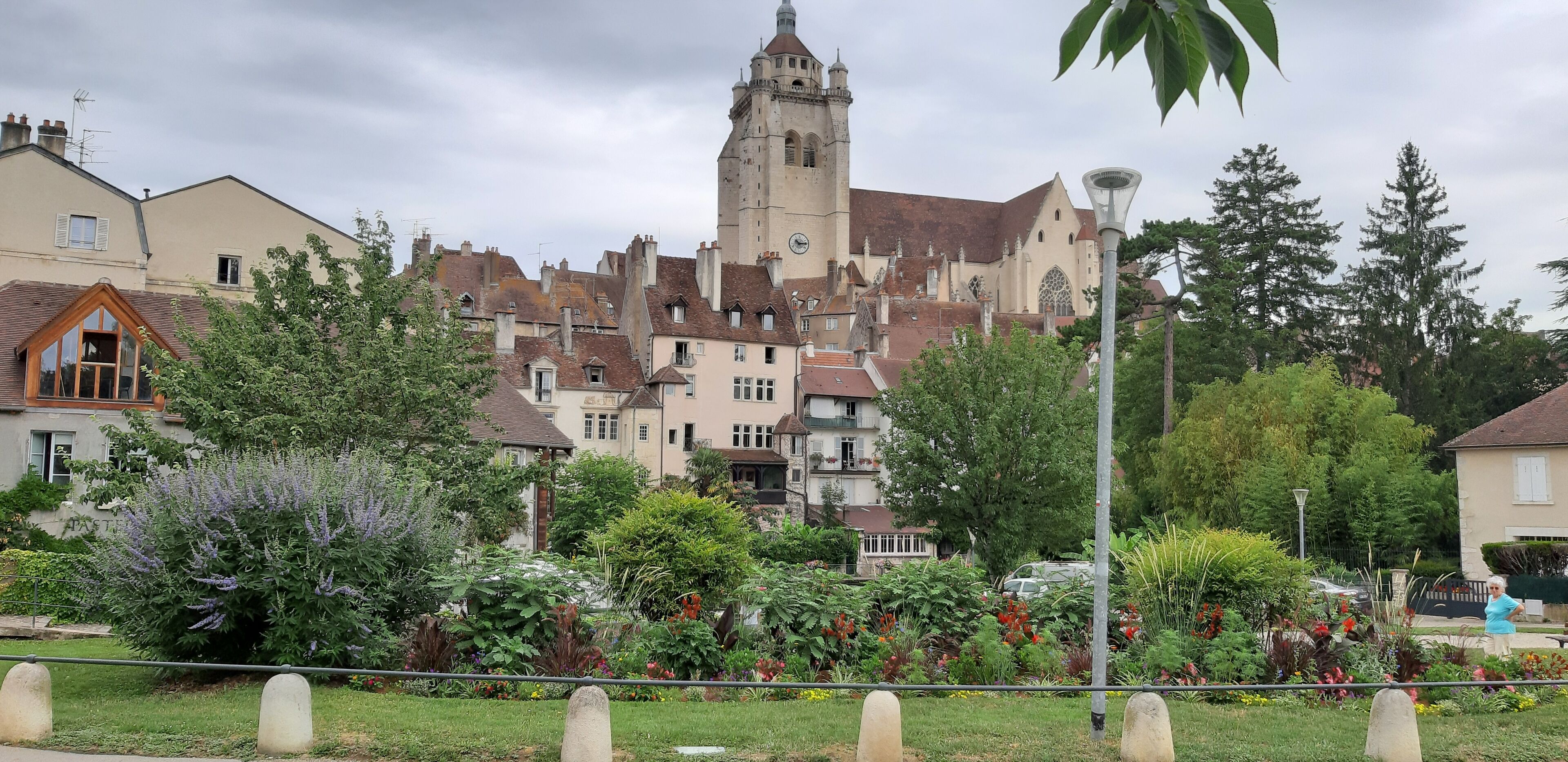 A historic building with a prominent tower, surrounded by lush gardens and residential buildings.