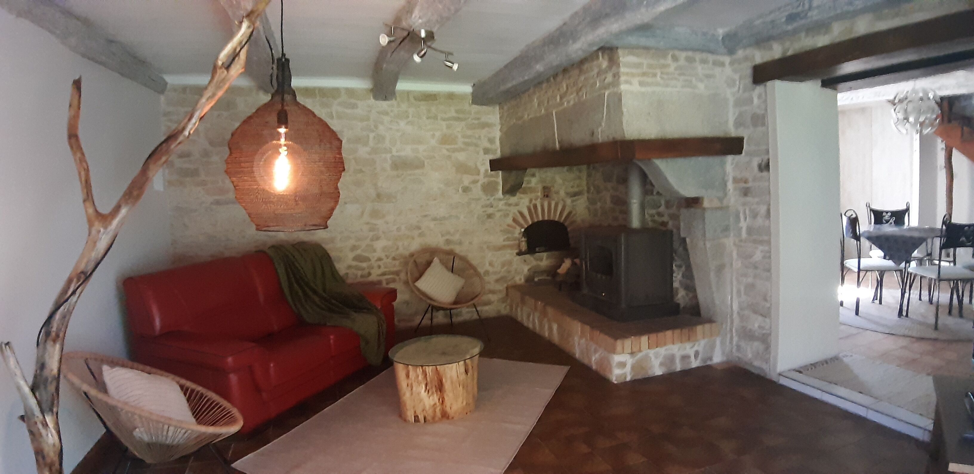 A cozy living room with a red sofa, a wooden coffee table, and a stone wall.