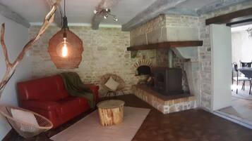 A cozy living room with a red sofa, a wooden coffee table, and a stone wall.