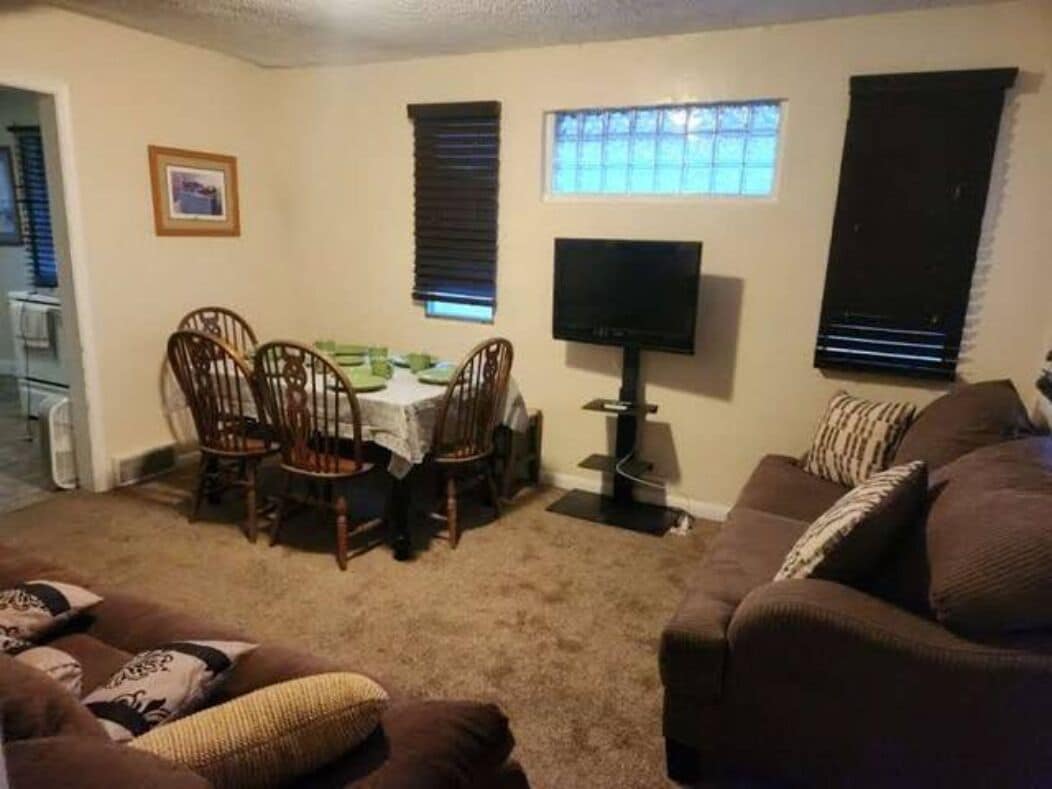 Ein Wohnzimmer mit Esstisch, Stühlen, Fernseher und einer Couch.