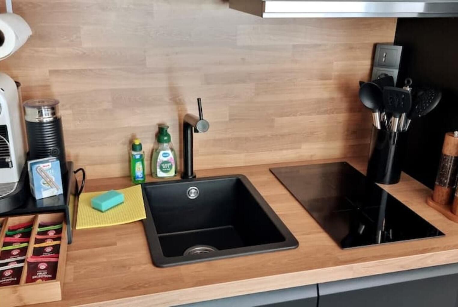 Eine moderne Küche mit einem schwarzen Spülbecken, einer Kaffeemaschine und einem Messerblock auf der Arbeitsfläche.