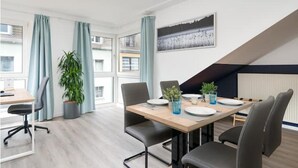 A modern conference room with a wooden table, grey chairs, and potted plants.