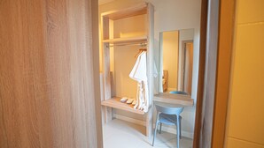 Un baño con tocador de madera, un espejo, un perchero para toallas y una silla.