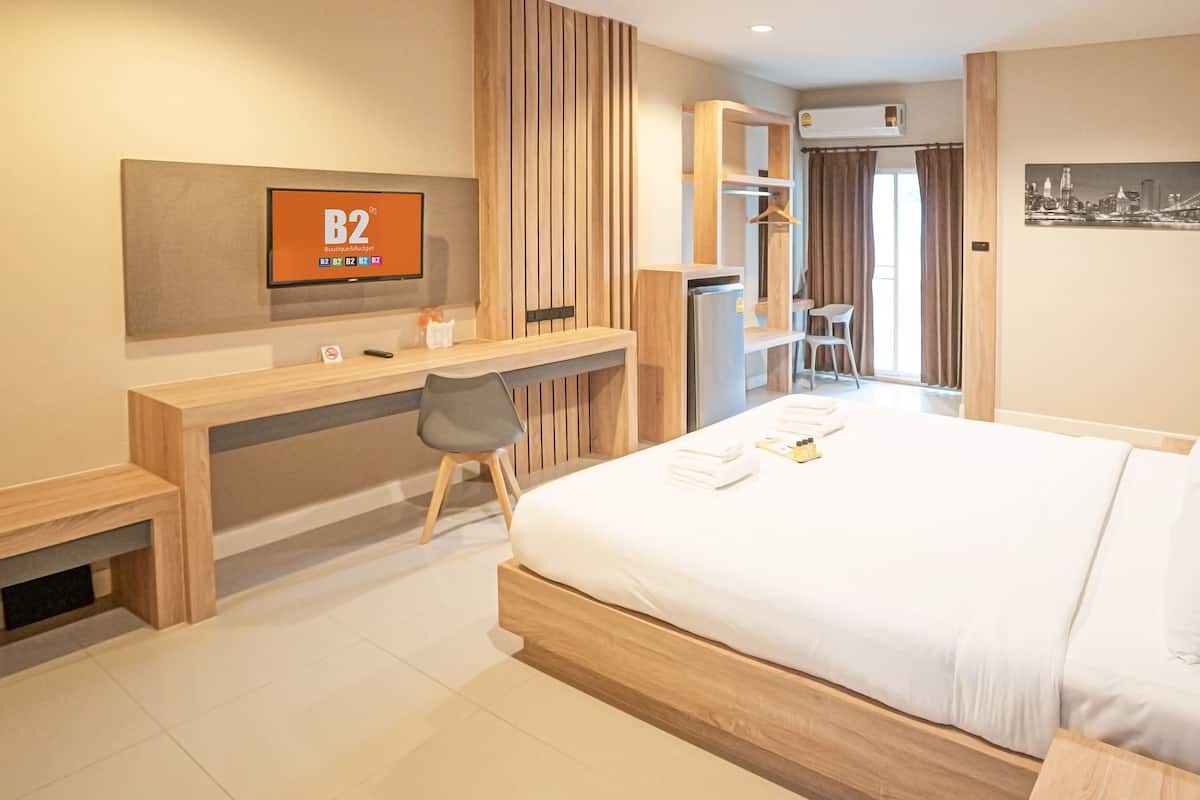 A hotel room with a bed, a desk, a chair, a TV, and a wardrobe.
