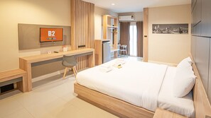 Une chambre d’hôtel comprenant un lit, un bureau, une chaise, une télévision et une armoire.