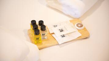A wooden tray with bottles of B2 conditioning shampoo, a bottle of shower gel, and a small bottle of lotion, along with a few white paper towels.