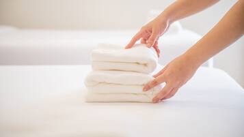 A stack of white towels on a bed.