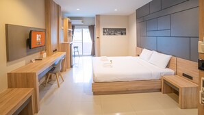 Una habitación de hotel moderna con una cama grande, muebles de madera, un televisor de pantalla plana y vistas a la ciudad.