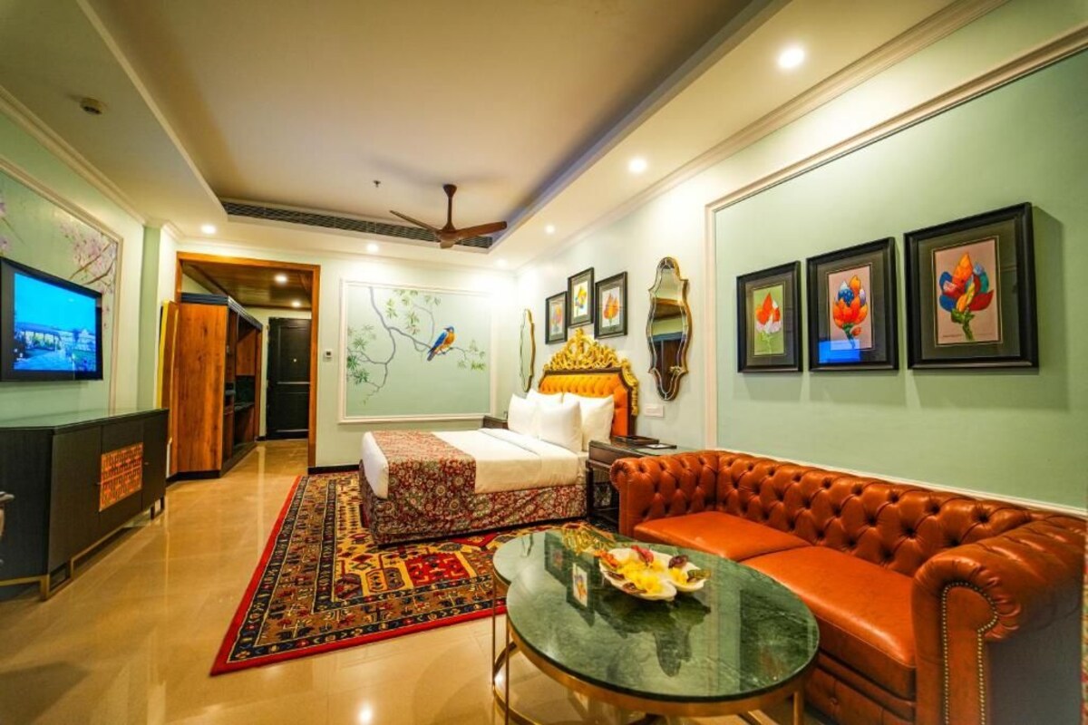 A hotel room with a bed, a sofa, a TV, and a dining table.
