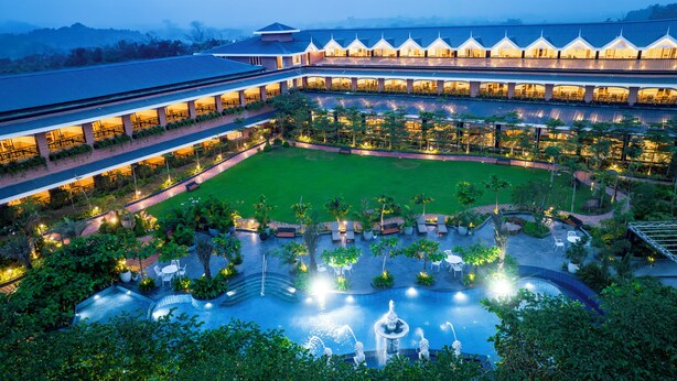 A hotel with a large courtyard, multiple dining areas, and a swimming pool with fountains. - Mayfair Oasis Resort & Convention (Jharsuguda)