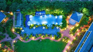 An aerial view of a landscaped area with a swimming pool, seating areas, and surrounding greenery. - Mayfair Oasis Resort & Convention (Jharsuguda)