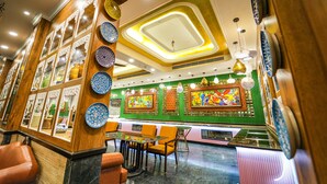 A restaurant interior with a central dining area, multiple seating options, and a decorative ceiling. - Mayfair Oasis Resort & Convention (Jharsuguda)