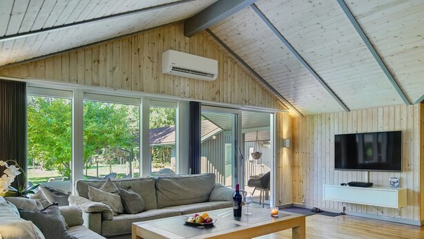 Un salon moderne avec un plafond en bois, de grandes fenêtres, un canapé, une table basse et un téléviseur.