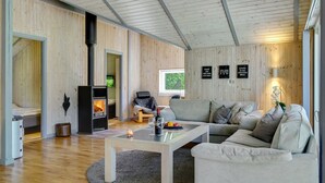 Un salon moderne avec un canapé, une table basse, une cheminée et une vue sur l’extérieur.