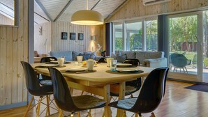 Un espace repas avec une table en bois, des chaises noires et un luminaire suspendu.