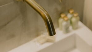 Une salle de bain avec un lavabo blanc, deux robinets dorés et un miroir au-dessus du lavabo.