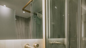 Une salle de bain moderne avec un grand lavabo blanc, une cabine de douche en verre et un miroir doté d’un cadre en bois.