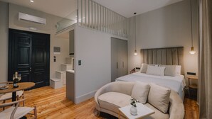 Une chambre moderne avec un lit, un canapé, une petite table et un escalier menant à un niveau supérieur.