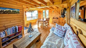 L’intérieur d’un chalet en bois comprend un coin repas, un canapé et une bibliothèque.