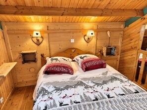 A wooden cabin room with a bed, two wall-mounted lamps, and a view of snowy mountains. - Chalet Les étoiles, vue Mont Blanc*** (Tresserve)