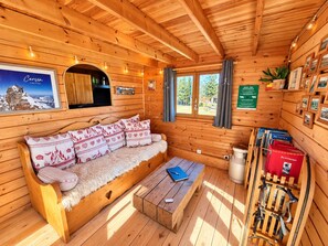 A cozy wooden cabin interior with a sofa, a small table, and a sauna area.