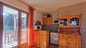 A compact kitchen with wooden cabinets, a refrigerator, and a microwave.