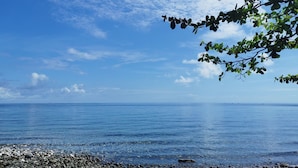 Orilla rocosa con agua tranquila y cielo despejado.