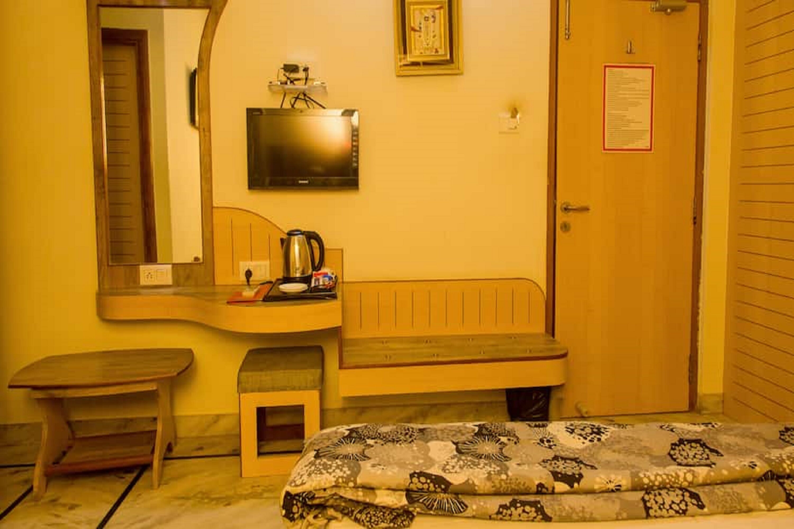 Un dormitorio pequeño y acogedor con una cama de madera, una mesita de noche, un espejo, un televisor y una puerta con un aviso.