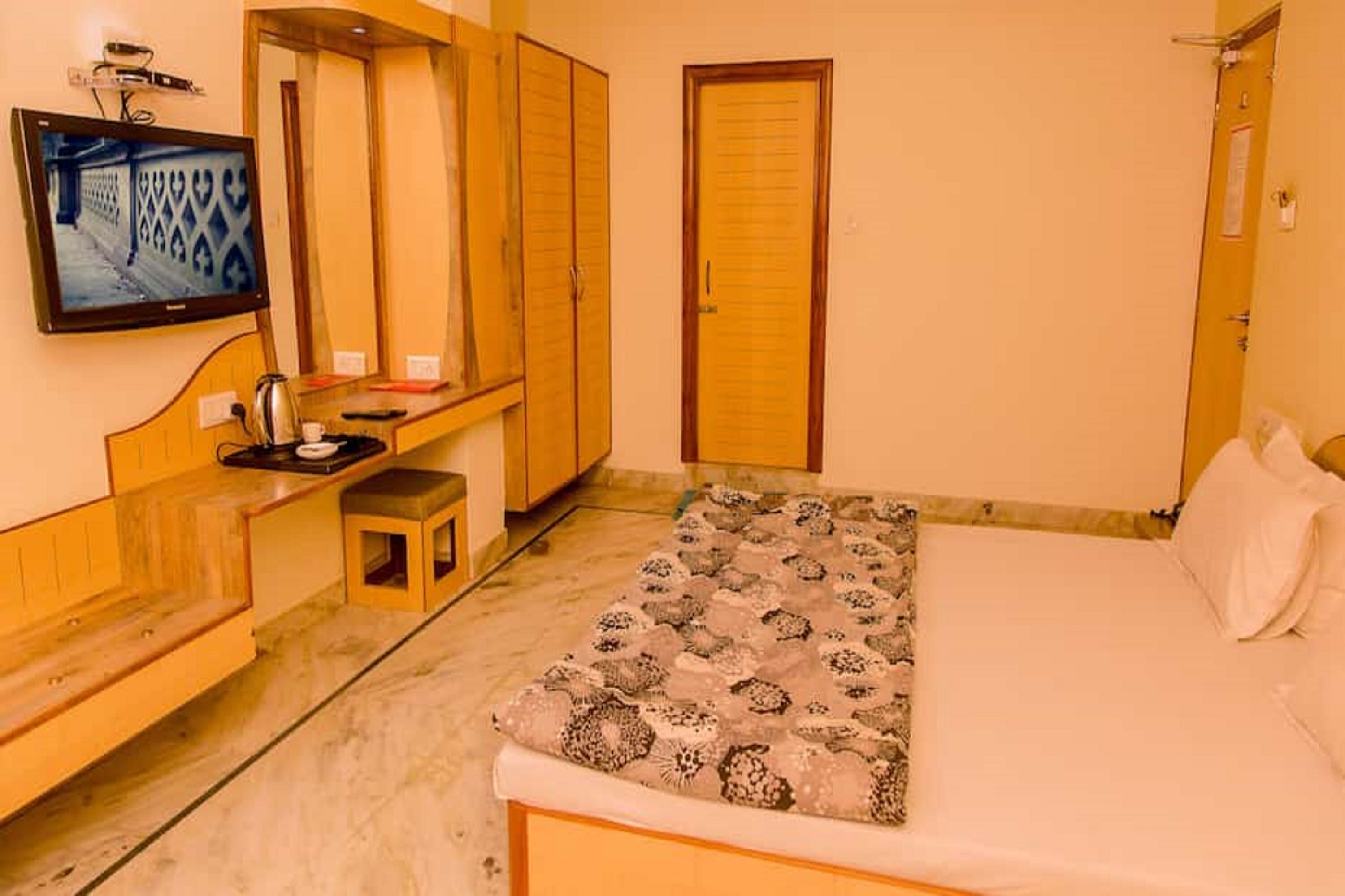 Une chambre à coucher comprenant un lit, un petit tabouret, une télévision et des armoires en bois.