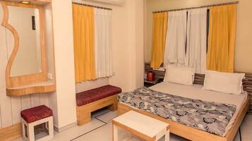 A bedroom with a bed, a bench, a small table, and a mirror.