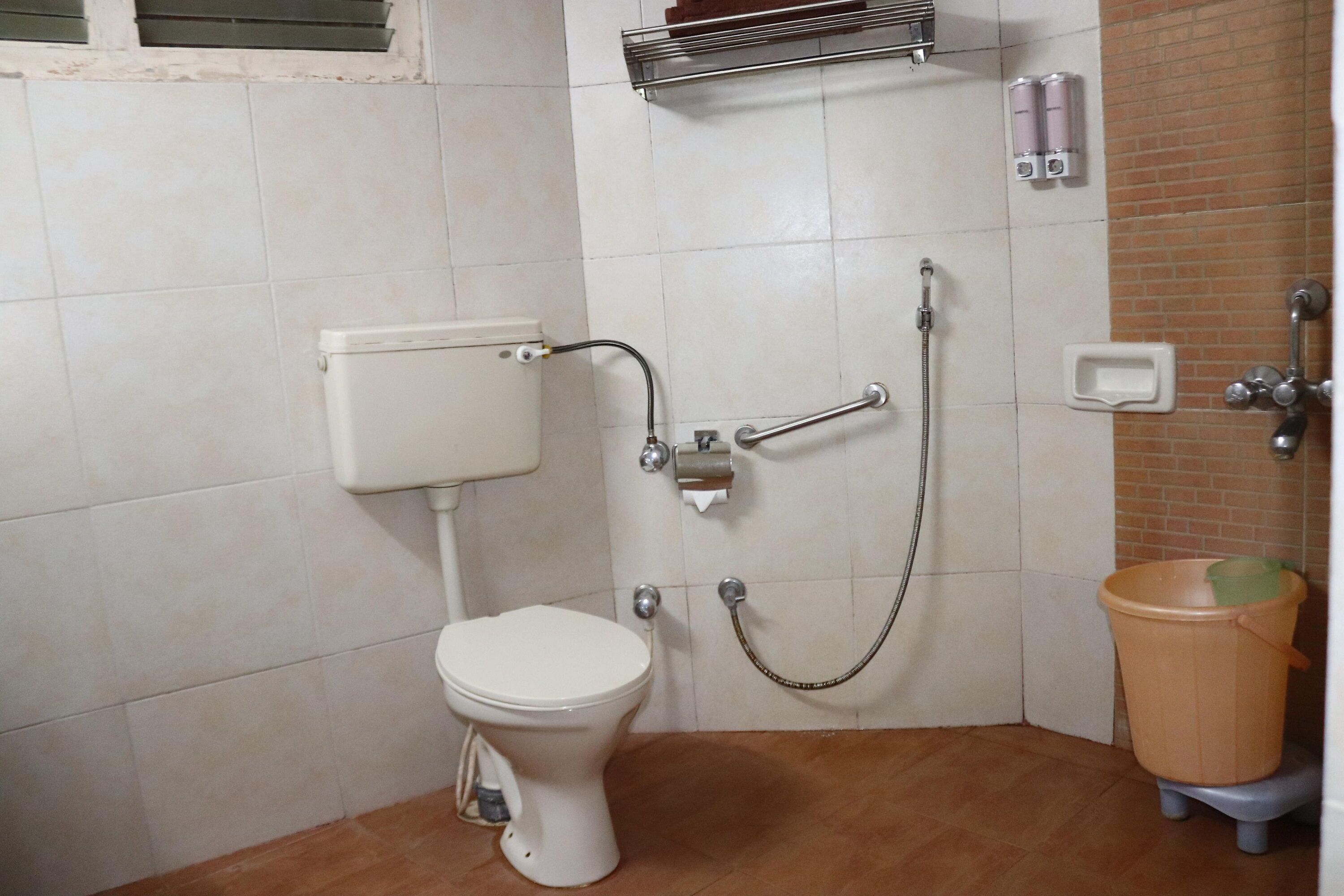 Un baño pequeño con inodoro, ducha y un cubo de basura.