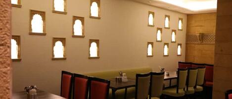 A restaurant with a high ceiling, patterned wall, and multiple seating areas including booths and tables.