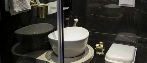 Une salle de bain moderne avec un lavabo en marbre noir, des toilettes blanches et un bidet.
