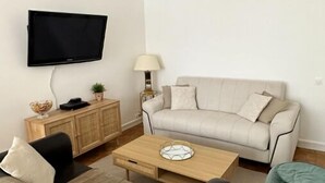 A modern living room with a sofa, a coffee table, a TV mounted on the wall, and a lamp.