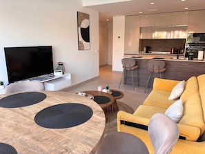 Una sala de estar moderna con televisor, mesa de comedor y sofá amarillo.