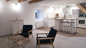 A modern kitchen with white cabinets, a central island with stools, and built-in appliances. - Maison Entièrement Rénovée ,à 600m de la mer Ideale Pour Passer de Bons Moments! (Plounéour-Brignogan-plages)