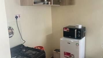 A compact kitchen with a gas stove, a microwave, and a refrigerator.