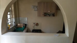 A small kitchen with a sink, a stove, and a microwave. There is a window with a view of the outside.